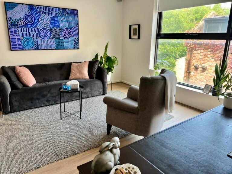 A Unison therapy room in Carlton with a grey sofa, soft cushions, plants and natural light